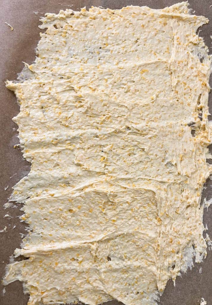 sourdough discard cracker dough spread thinly over a sheet of parchment paper