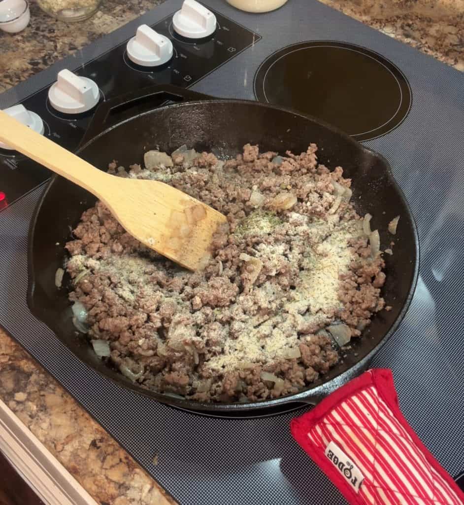 browned hamburger meat in a cast iron skillet with garlic powder
