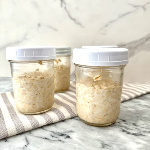 overnight oats in pint sized mason jars on a marble pastry board