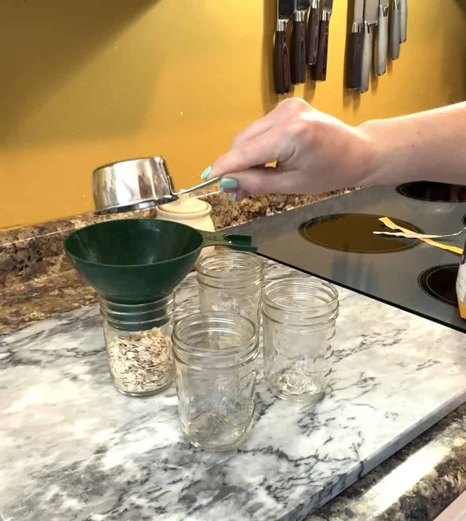 measuring oats and pouring them in pint size mason jars