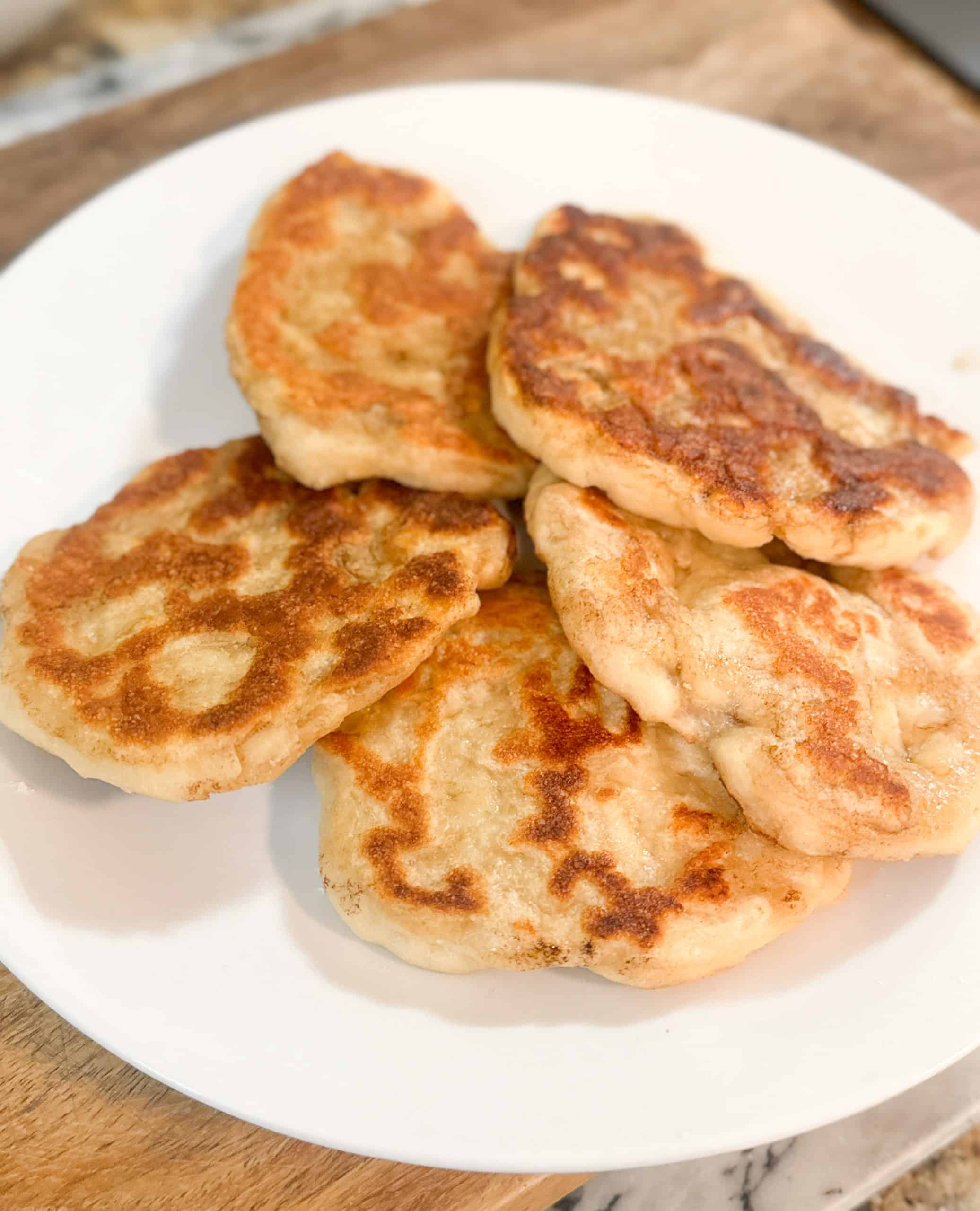 golden sourdough naan bread sitting on a white plate