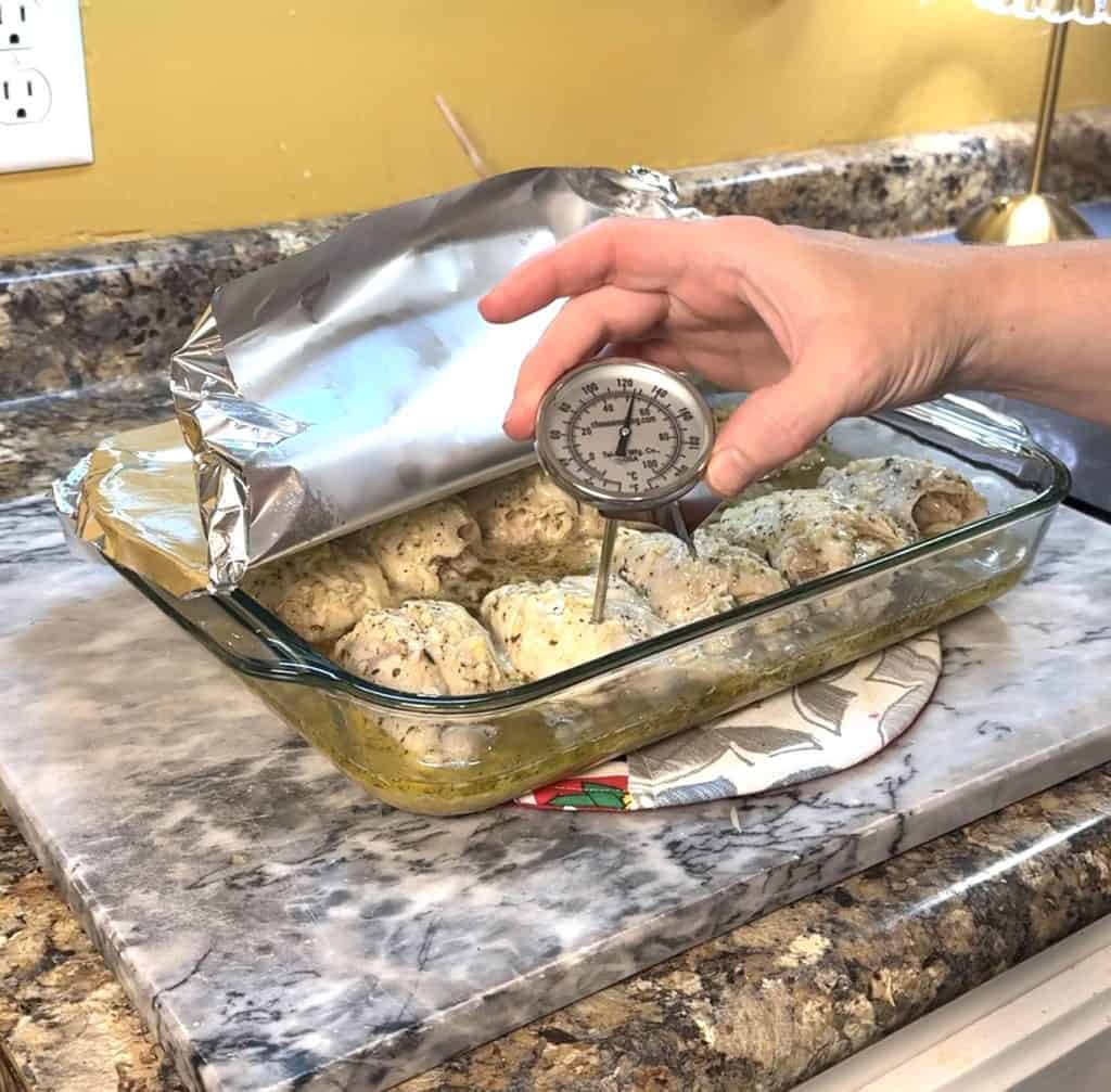 using a thermometer to check the internal temp of the chicken