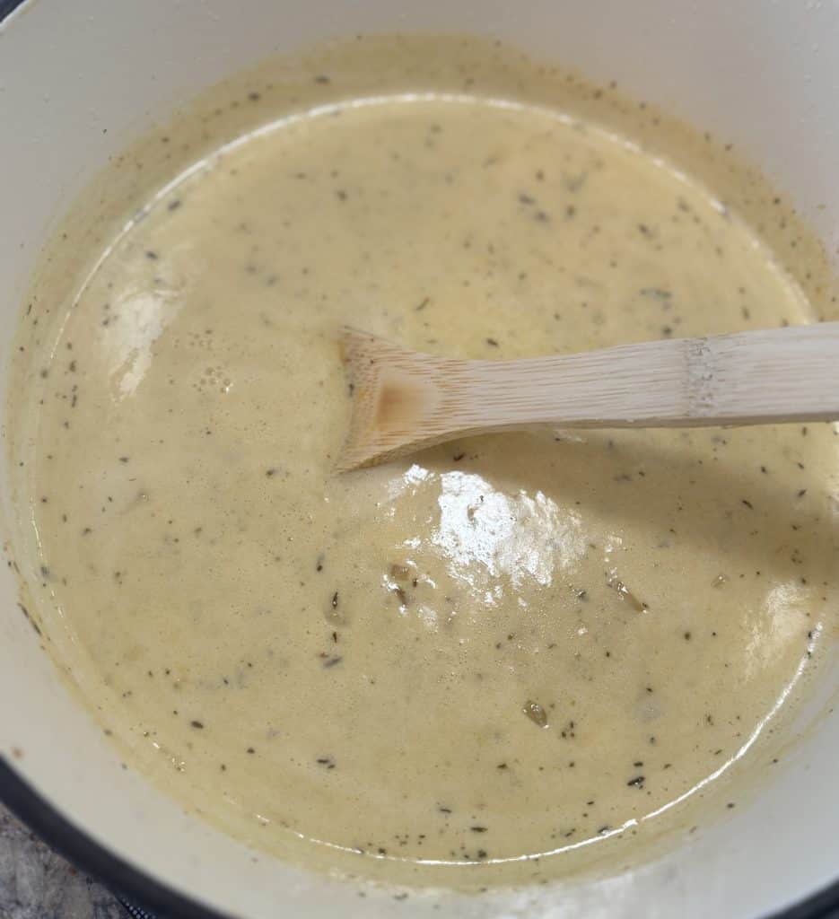 finished beer and cheddar soup in a large dutch oven with a wooden spoon