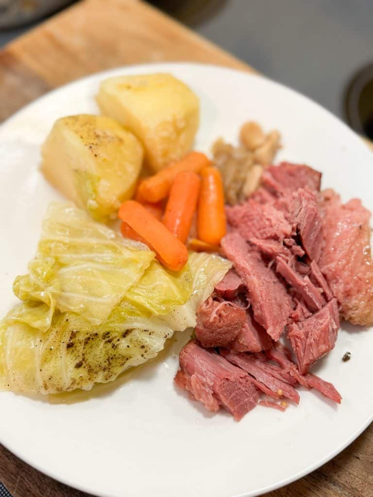 corned beef, cabbage, carrots and potatoes on a white ceramic plate