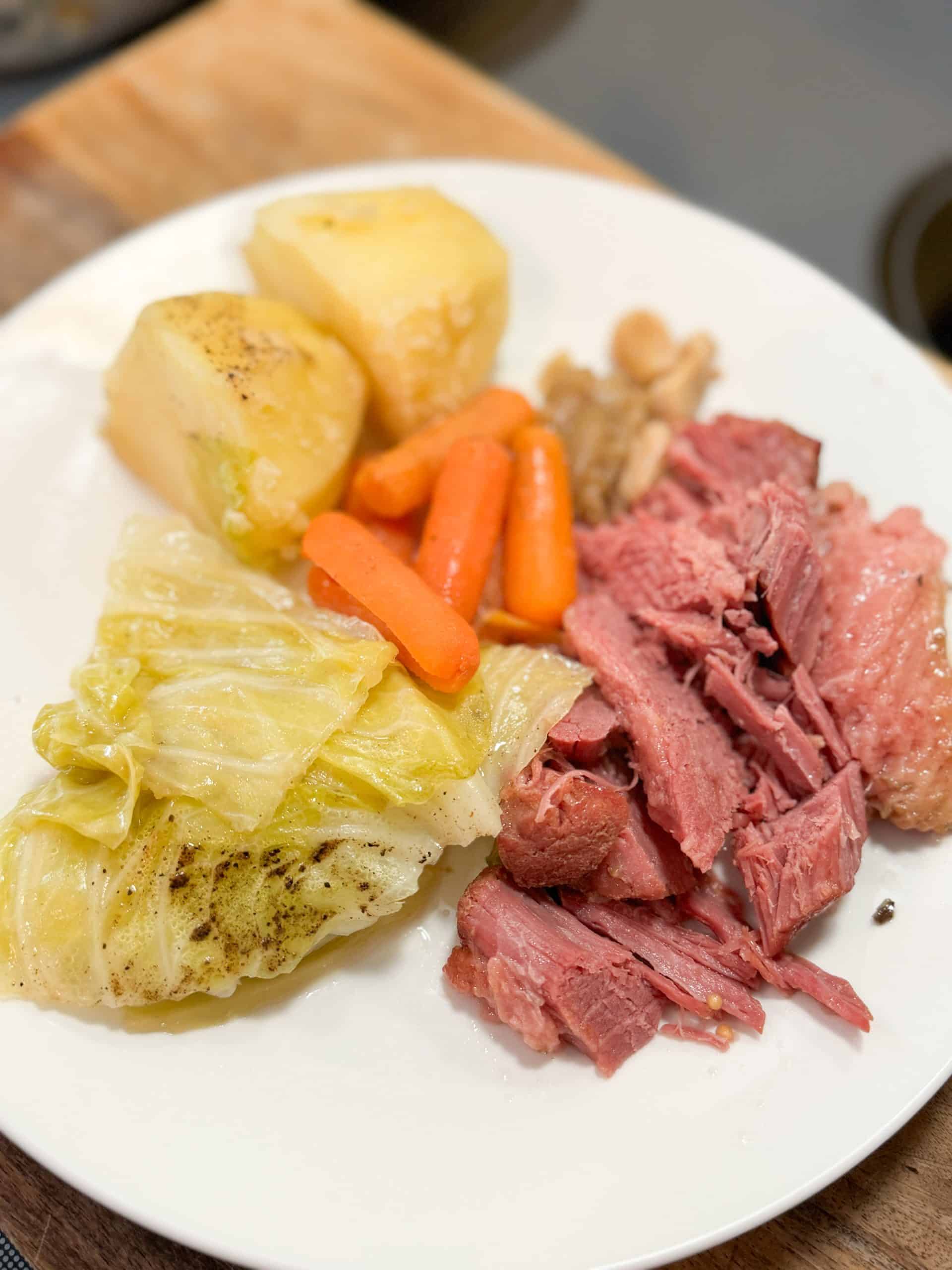 corned beef, cabbage, carrots and potatoes on a white ceramic plate