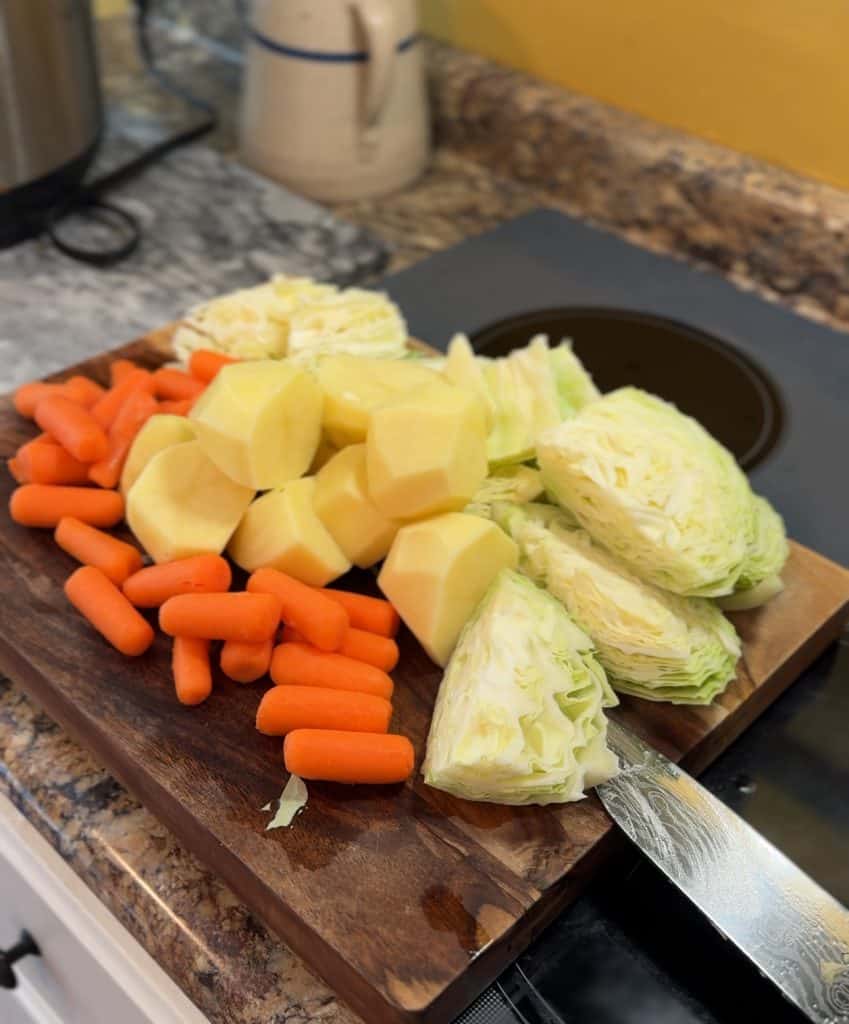 diced cabbage, potatoes and carrots on a wood cutting board