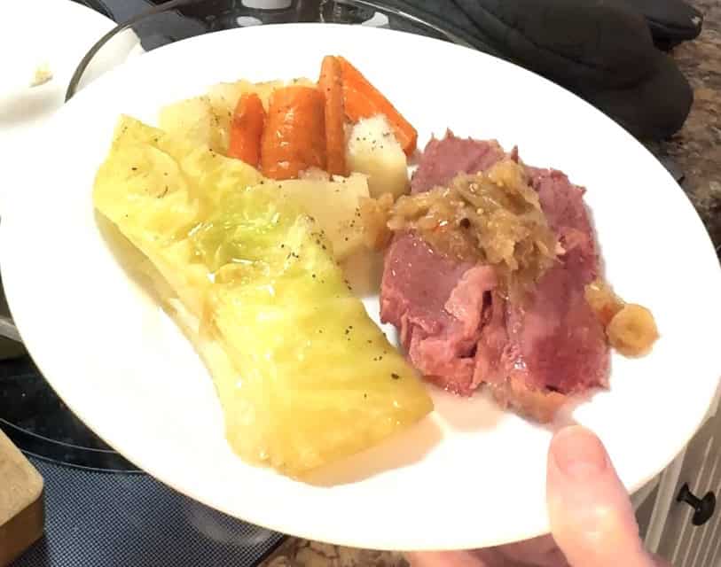 corned beef with cabbage, potatoes and carrots on a white plate