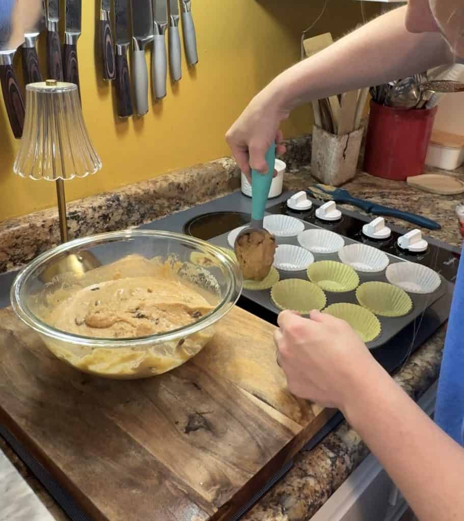 cinnamon raisin muffin batter being scooped into a muffin tin