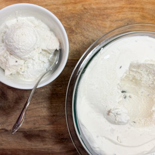 coconut lavender ice cream scooped from a large bowl to a smaller bowl