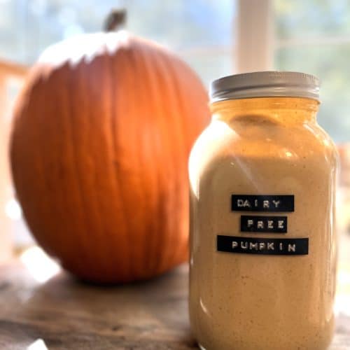dairy free pumpkin spice creamer in a glass mason jar on a wooden counter sitting next to a pumpkin