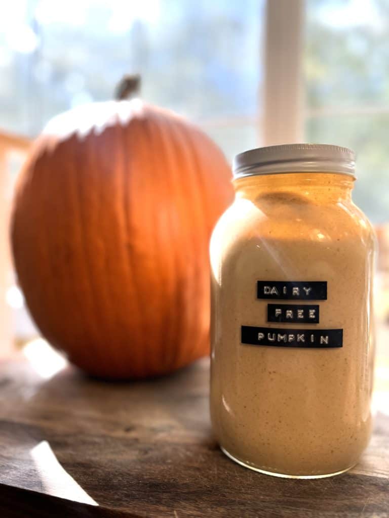 dairy free pumpkin spice creamer in a glass mason jar on a wooden counter sitting next to a pumpkin