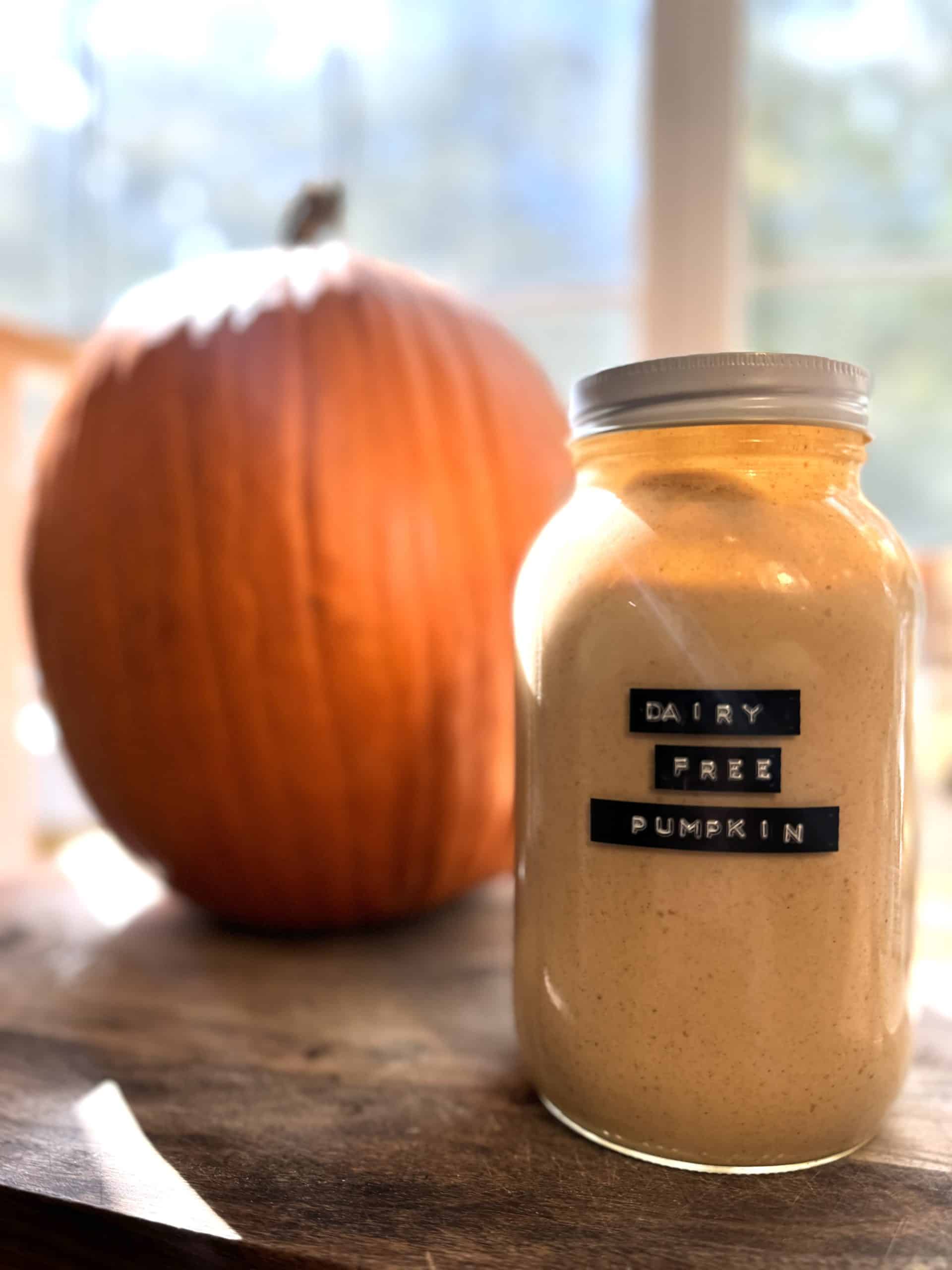 dairy free pumpkin spice creamer in a glass mason jar on a wooden counter sitting next to a pumpkin