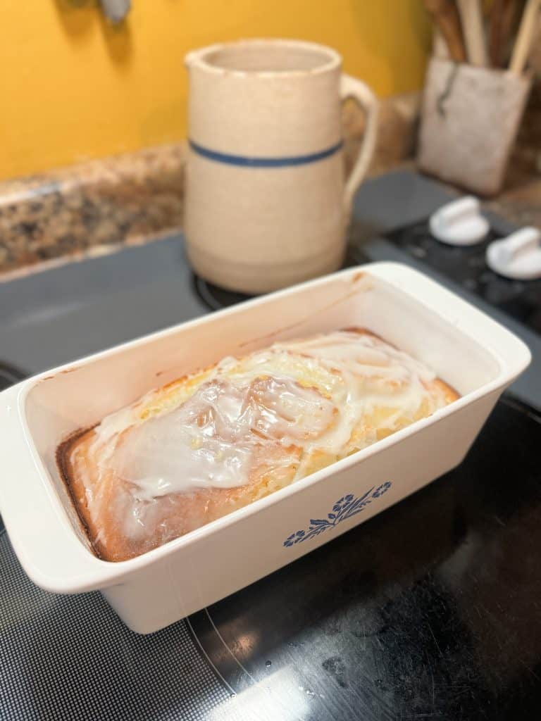 Glazed Sourdough Lemon Cake in a ceramic loaf pan sitting on a stove
