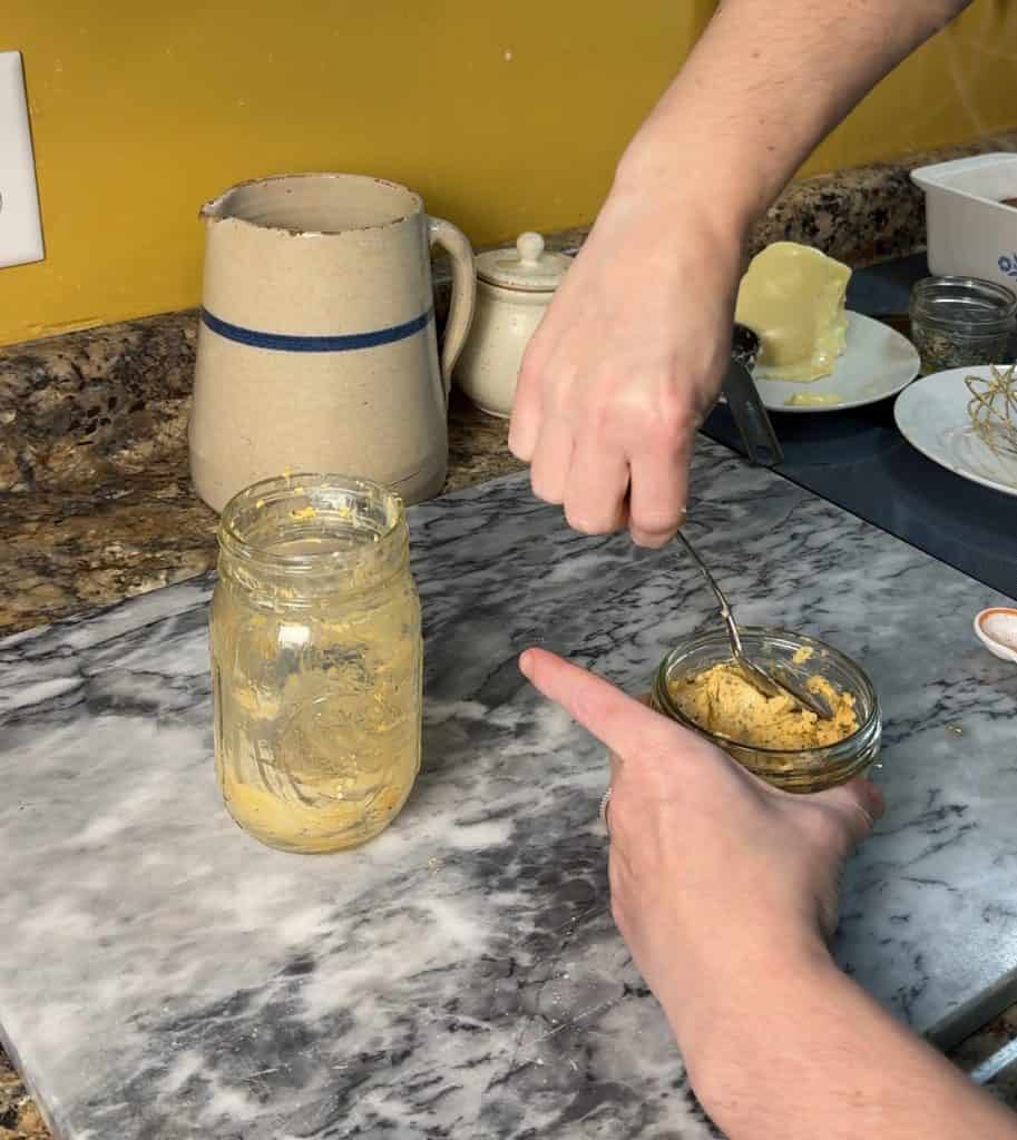 using a spoon to place the cowboy butter in an airtight container for storage.