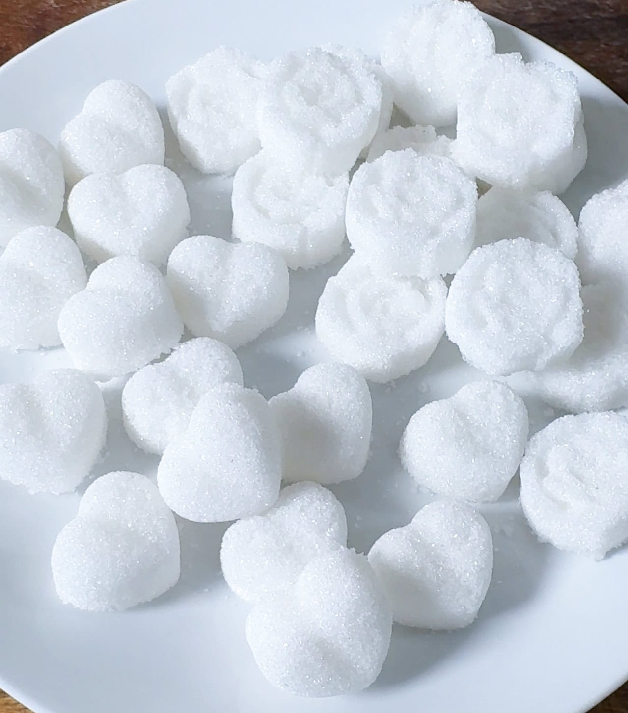 white sugar cubes shaped as hearts and flowers on a white plate