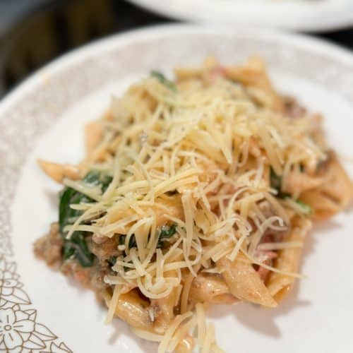 Instant Pot Creamy Tomato and Sausage Pasta on a white plate with a floral design