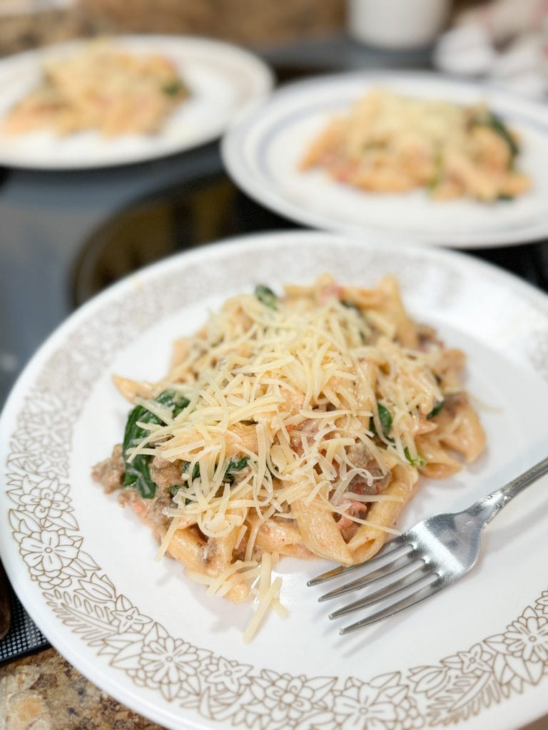 Creamy Tomato and Sausage Pasta on a white plate with a fork