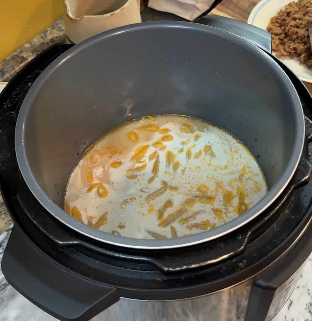 pasta submerged in chicken broth and heavy cream in an instant pot