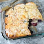 Lemon Glazed Blueberry Butter Swim Biscuits in a glass dish with one biscuit missing