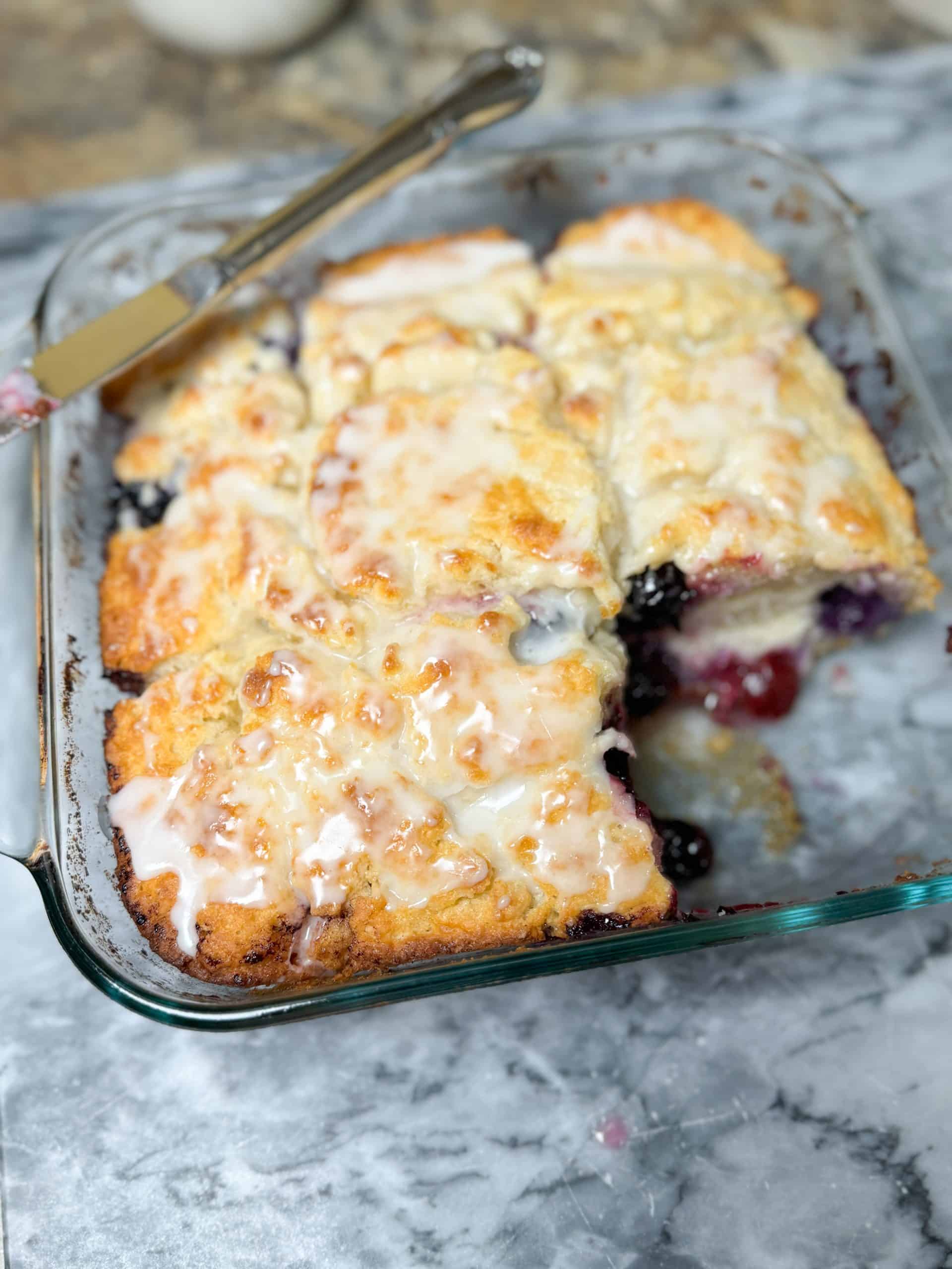 Lemon Glazed Blueberry Butter Swim Biscuits in a glass dish with one biscuit missing