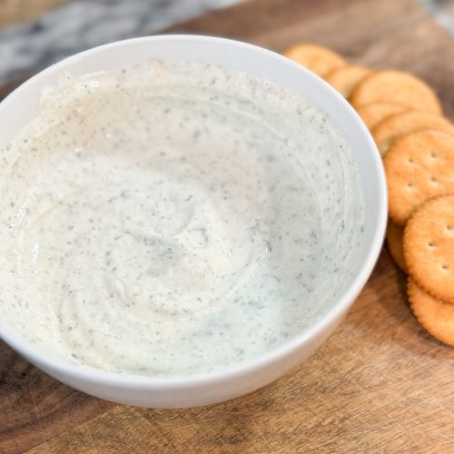 Greek Yogurt Ranch Dip in a white bowl sitting on a wood cutting board next to some crackers