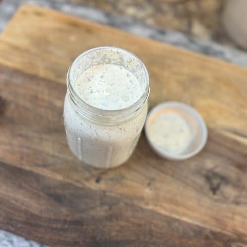Homemade Ranch Dressing in a mason jar sitting on a wooden cutting board