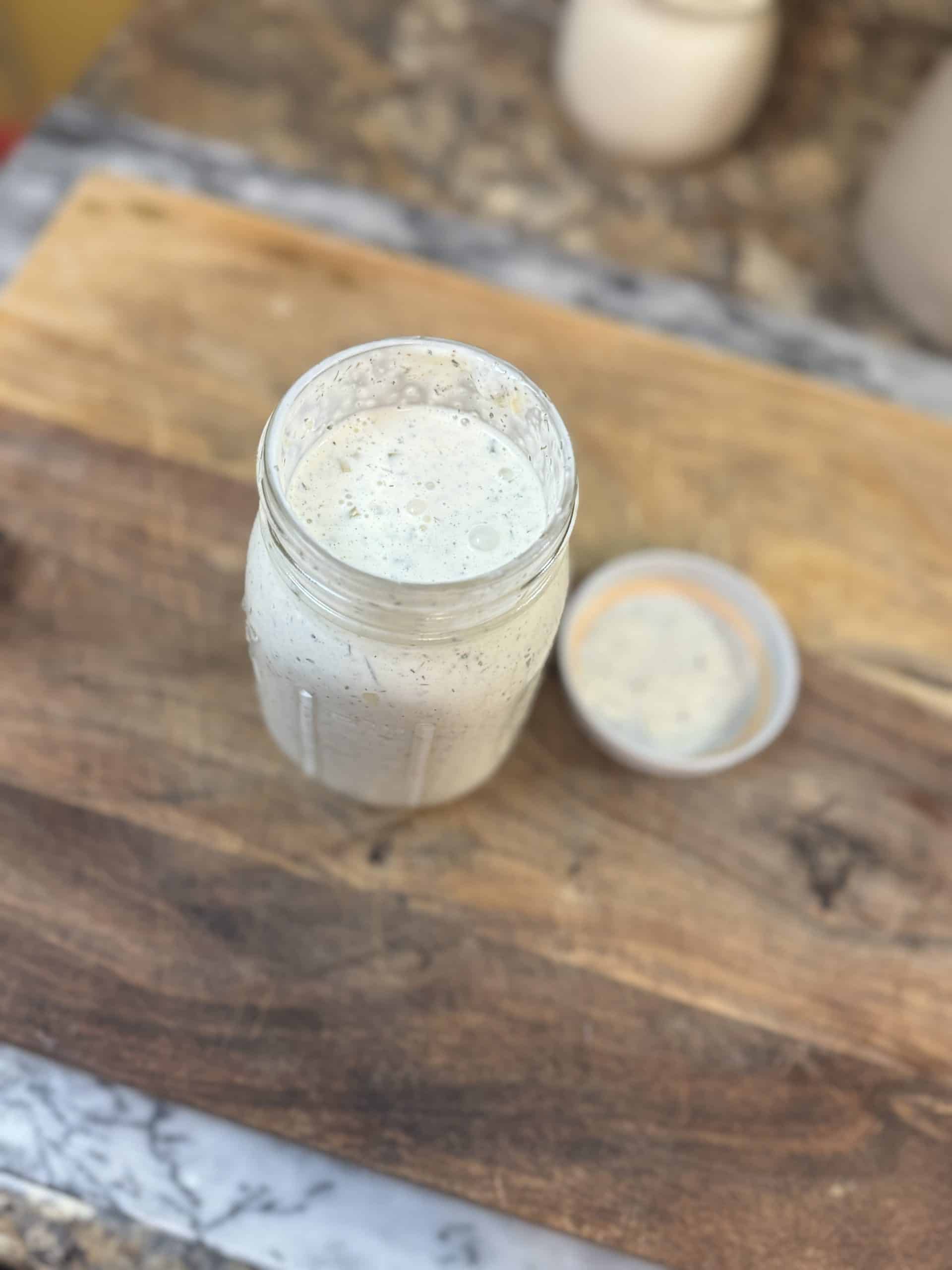 Homemade Ranch Dressing in a mason jar sitting on a wooden cutting board