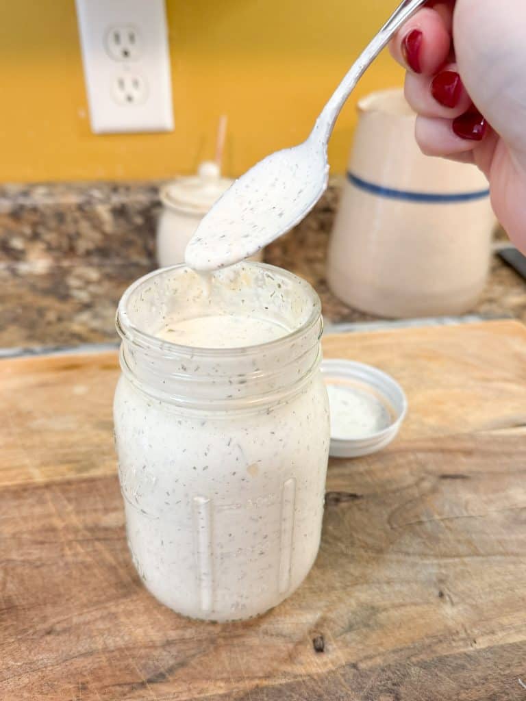 Homemade Ranch Dressing dripping off a spoon into a mason jar