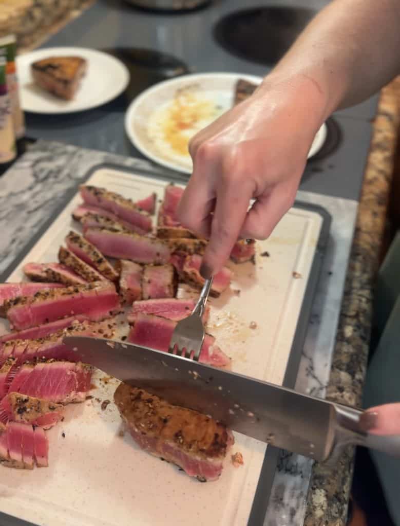 slicing ahi tuna steaks on a white cutting board