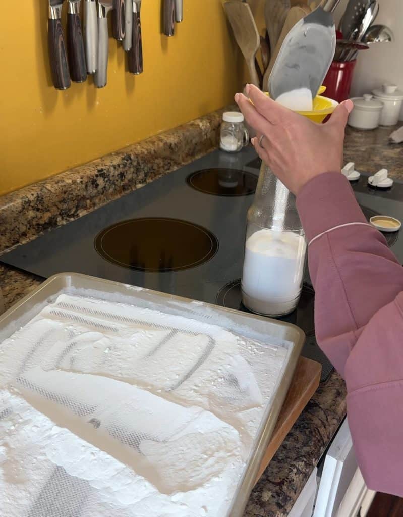 pouring the washing soda into a glass jar