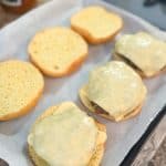 old fashioned hamburgers with melted cheese on top sitting inside hamburger buns