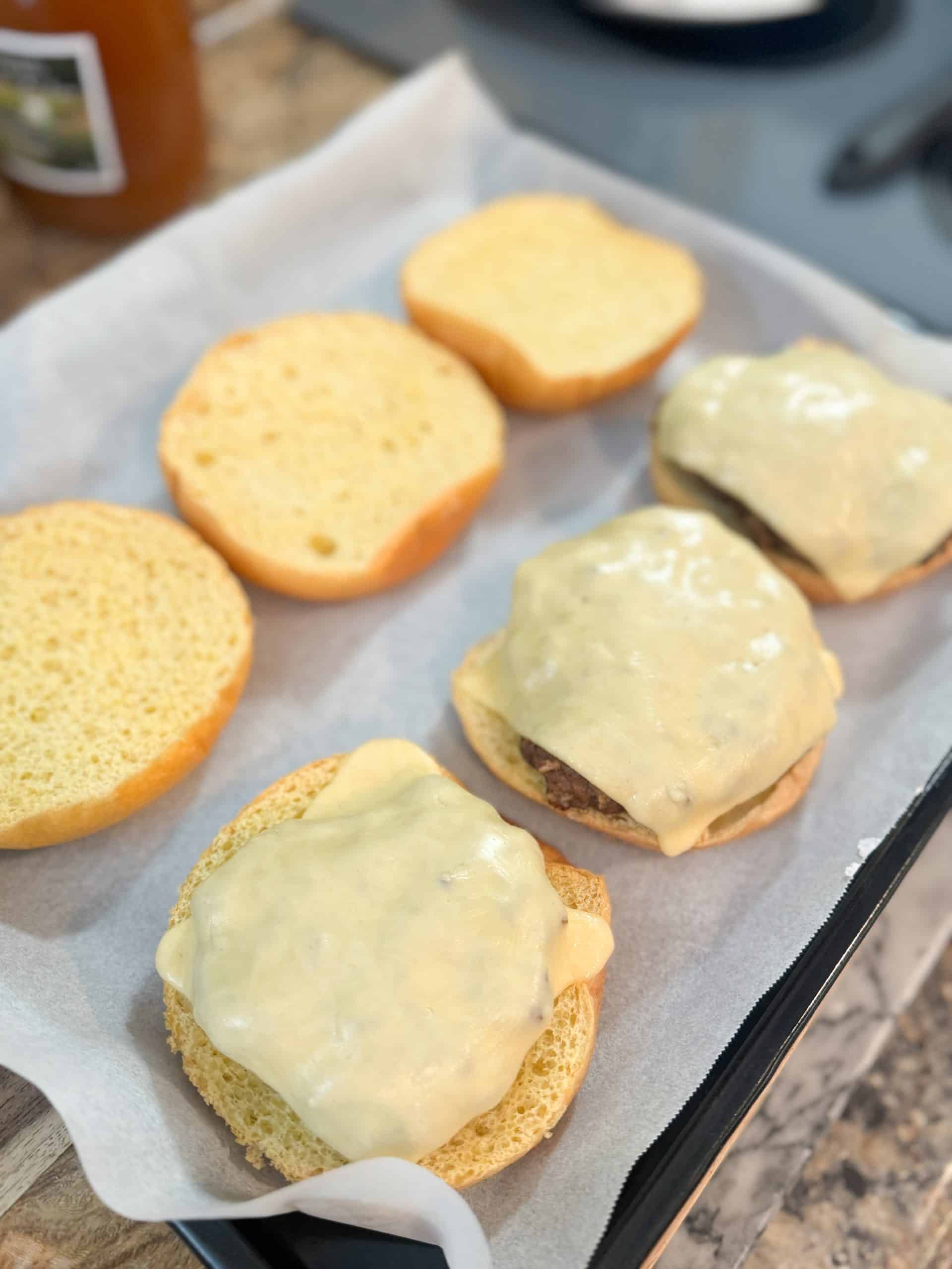 old fashioned hamburgers with melted cheese on top sitting inside hamburger buns