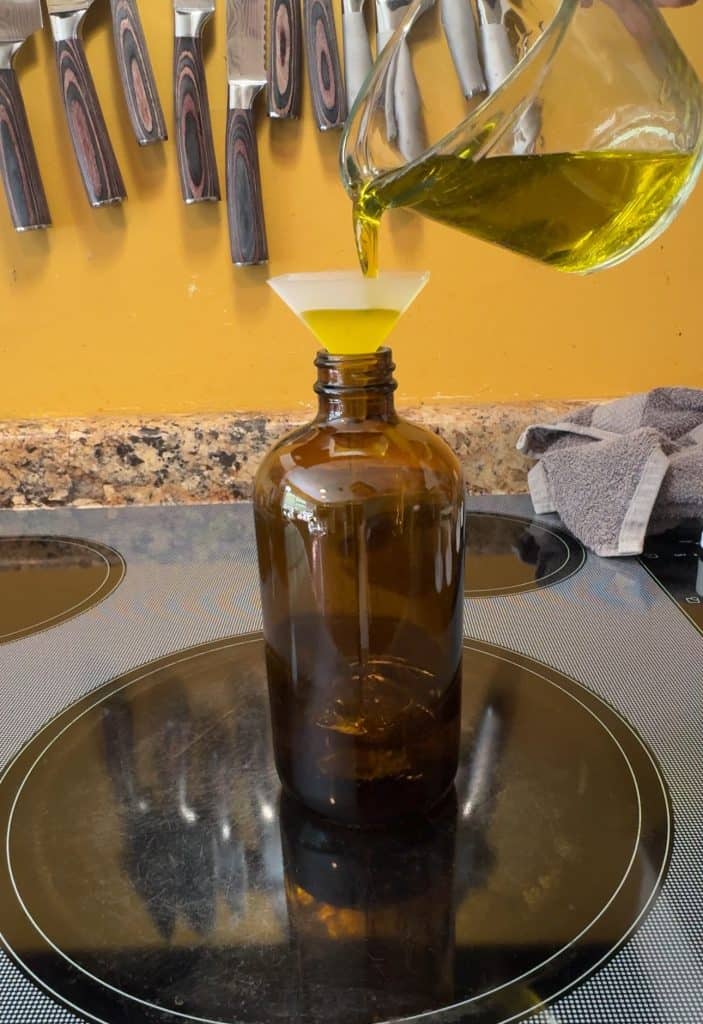 adding olive oil to an amber spray bottle