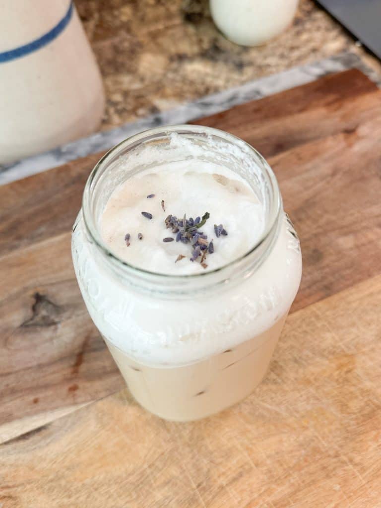 creamy lavender cold foam over iced coffee in a mason jar with lavender buds sprinkled on top