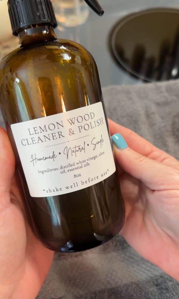 holding a bottle of DIY Wood Cleaner and Polish