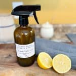 Natural DIY Wood Cleaner and Polish sitting next to a lemon sliced in half on a wood cutting board next to a microfiber cloth