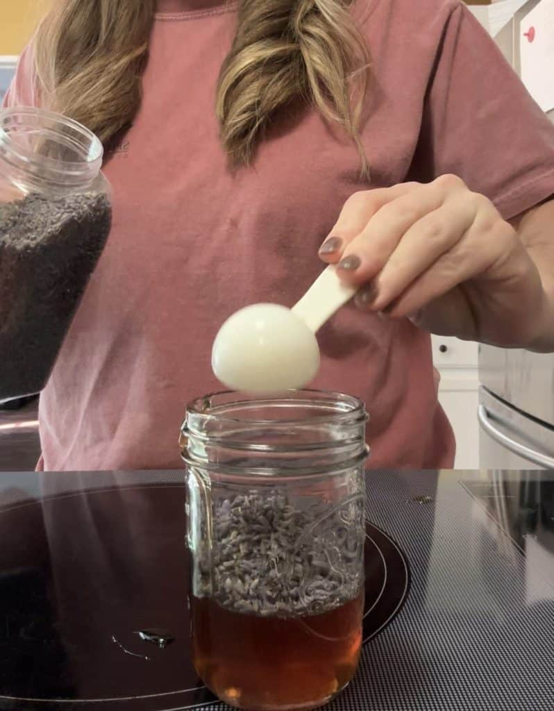 adding dried lavender buds to a jar of honey