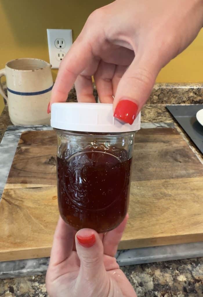 holding a glass jar full of lavender infused honey