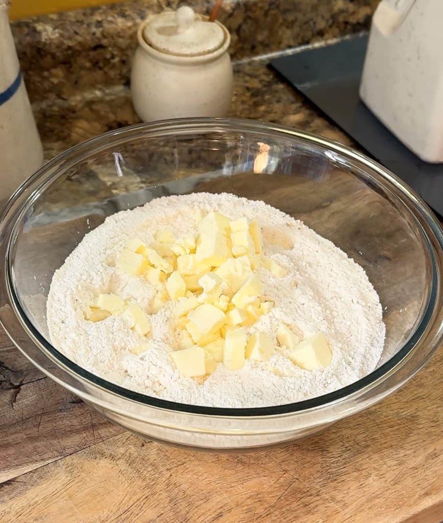 adding cubed butter to the dry ingredients for cheesy sausage and rosemary scones