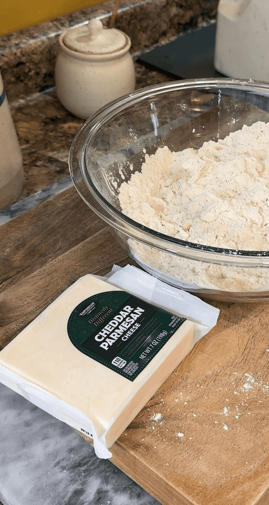 cheddar parmesan cheese sitting on a cutting board next to the scone flour mixture