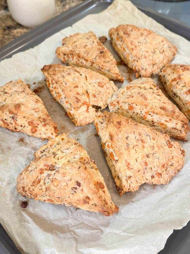golden brown cheesy sausage and rosemary scones on a parchment lined baking sheet