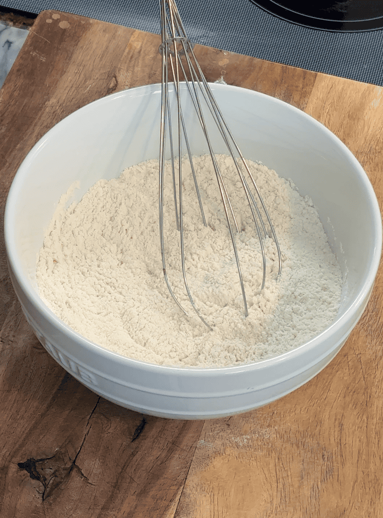 dry ingredients for egg roll wrappers in a mixing bowl with a whisk