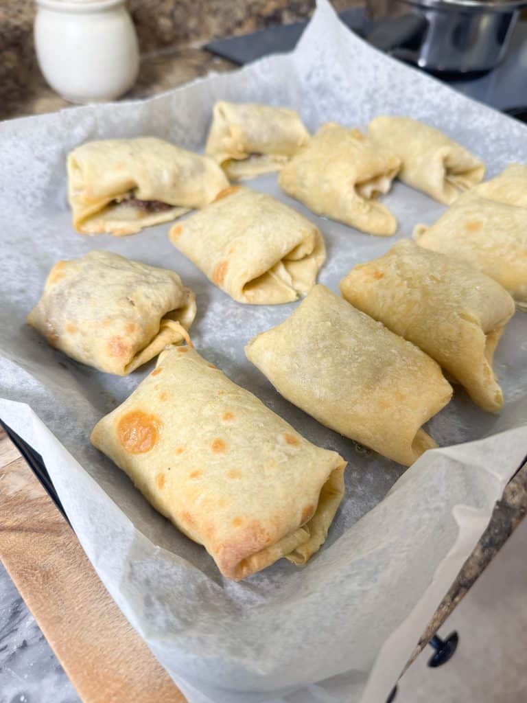cooked egg rolls on a parchment lined baking sheet