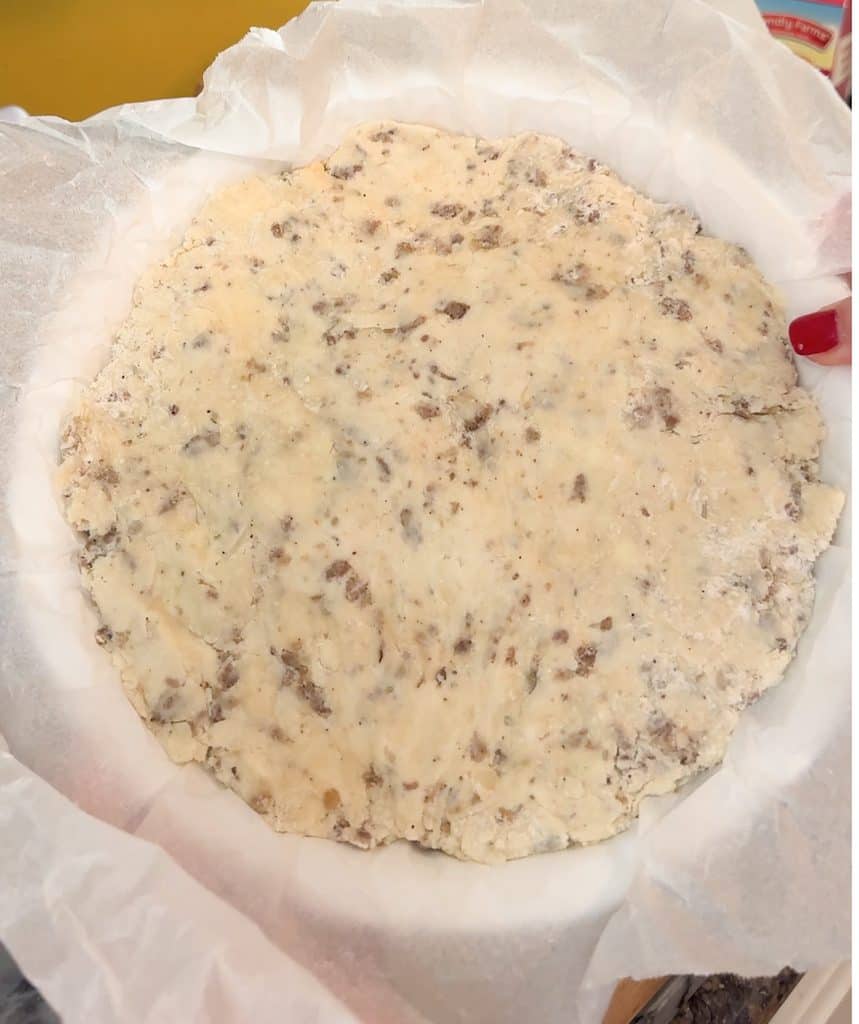 cheesy sausage and rosemary scone dough pressed nicely into a pie dish