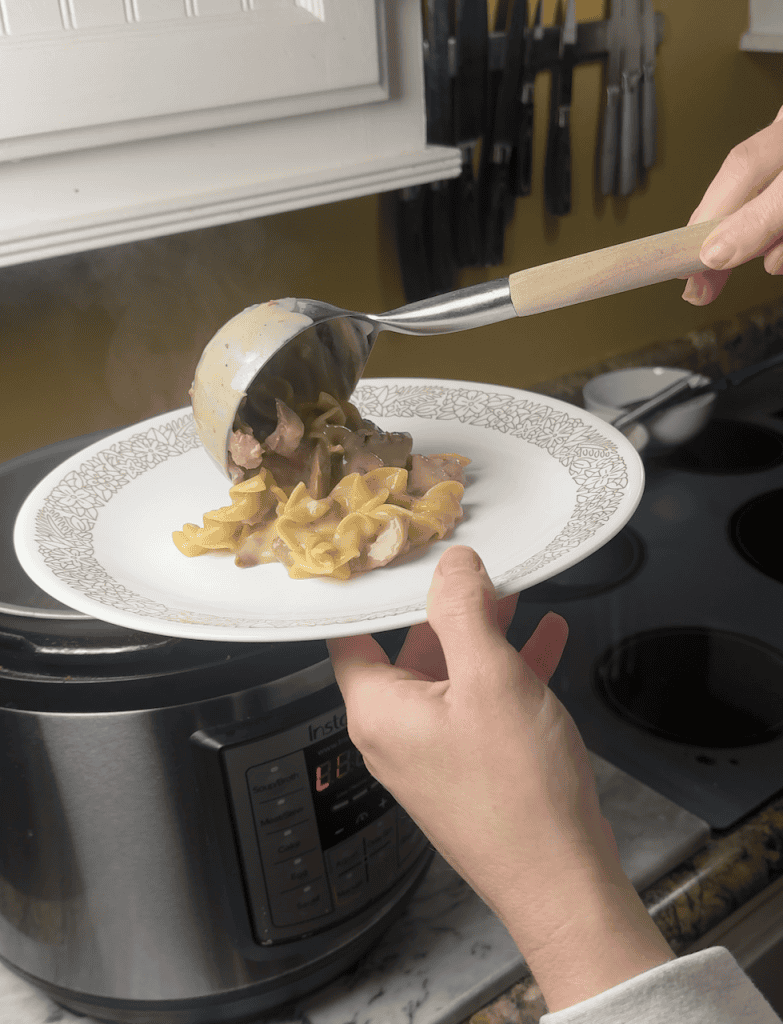 spooning the beef stroganoff onto a white plate