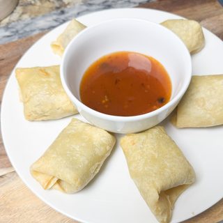 sweet and spicy chili sauce in a bowl in the middle of egg rolls