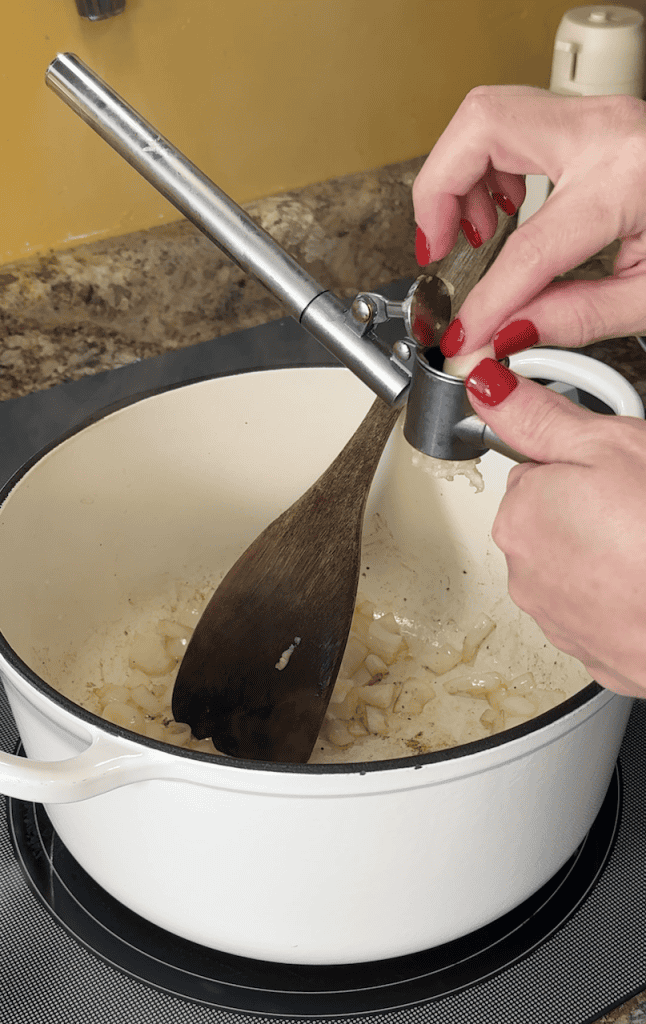 adding minced garlic in with diced yellow onion to saute in a large dutch oven