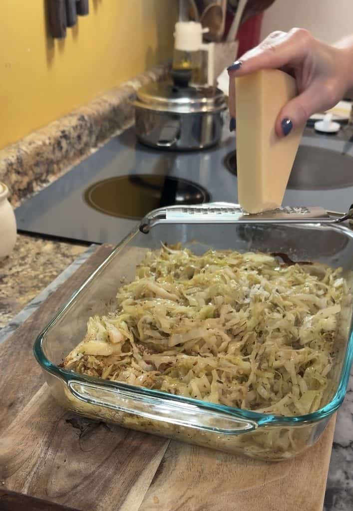grating fresh parmesan over buttery garlic parmesan baked cabbage