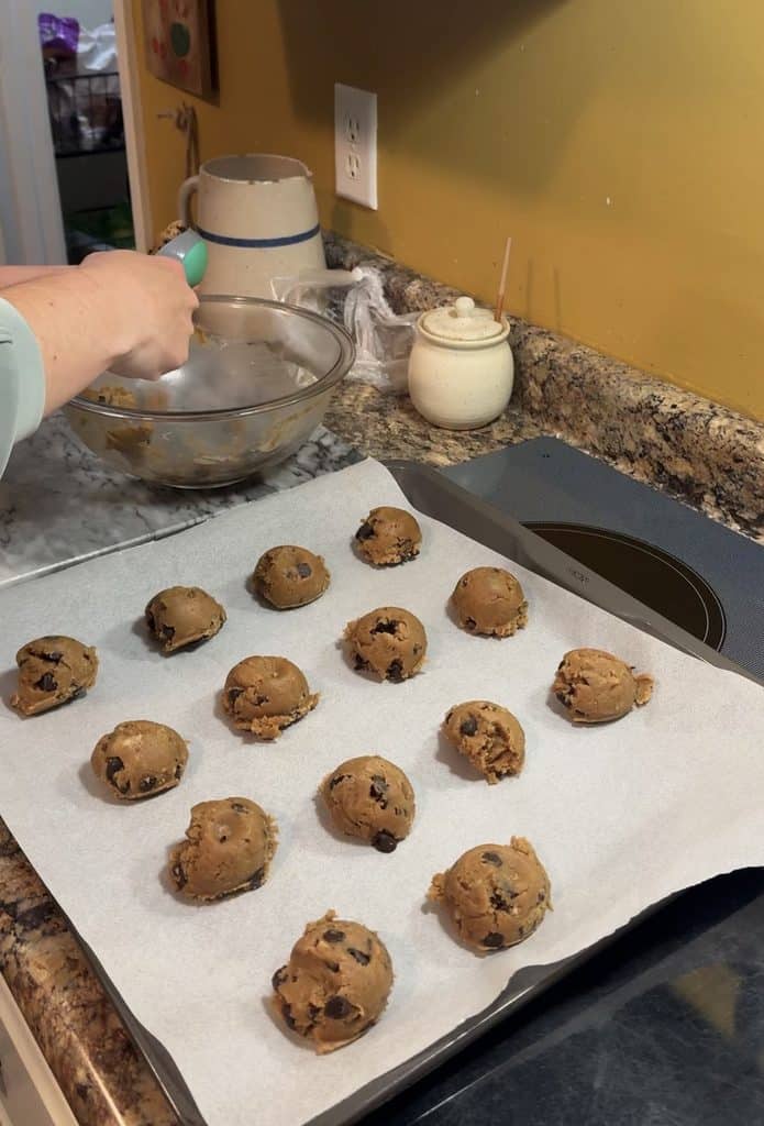 spooning brown butter chocolate chip cookie dough onto a parchment lined cooking sheet